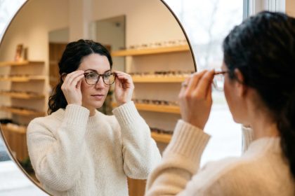 Femme essayant des lunettes en acétate écaille de tortue dans une boutique optique moderne avec des rangées de montures en arrière-plan