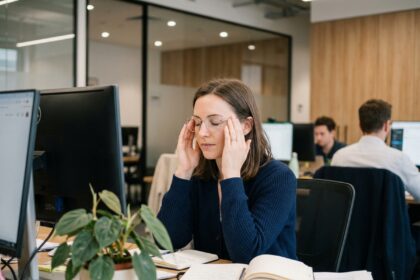 Femme en bureau se massant les tempes pour soulager le stress